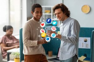 Two people engage with a smartphone amidst floating social media icons, in a bright, modern office setting with a woman working nearby.