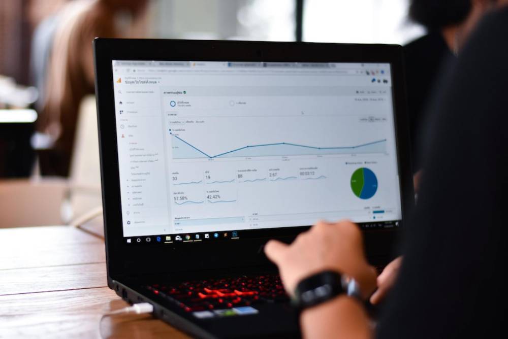 A person analyzing website analytics on a laptop, displaying graphs and statistics on a wooden table.