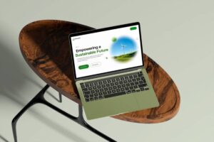 A green laptop displays a webpage about empowering a sustainable future, resting on a stylish wooden table.