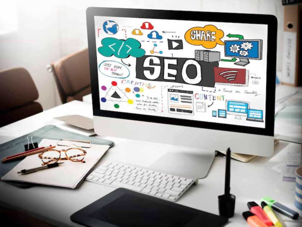 A computer screen displaying a colorful SEO and content strategy mind map, surrounded by office supplies on a desk.
