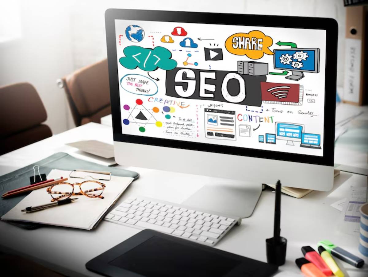 A computer screen displaying a colorful SEO and content strategy mind map, surrounded by office supplies on a desk.