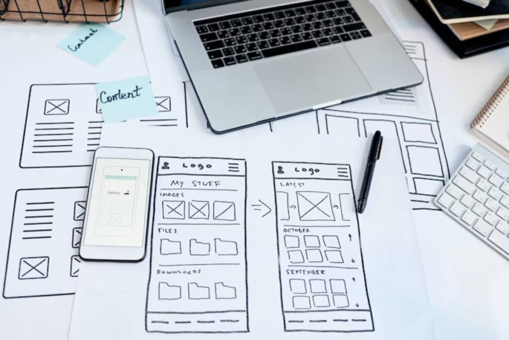 A workspace with wireframe sketches, a smartphone, laptop, keyboard, and sticky notes labeled 'Content.' Tools for web design and planning.