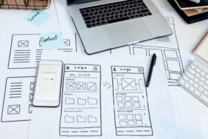 A workspace with wireframe sketches, a smartphone, laptop, keyboard, and sticky notes labeled 'Content.' Tools for web design and planning.